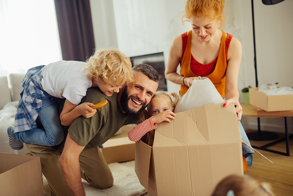 Happy family playing in moving boxes in their new house after receiving home inspection services
